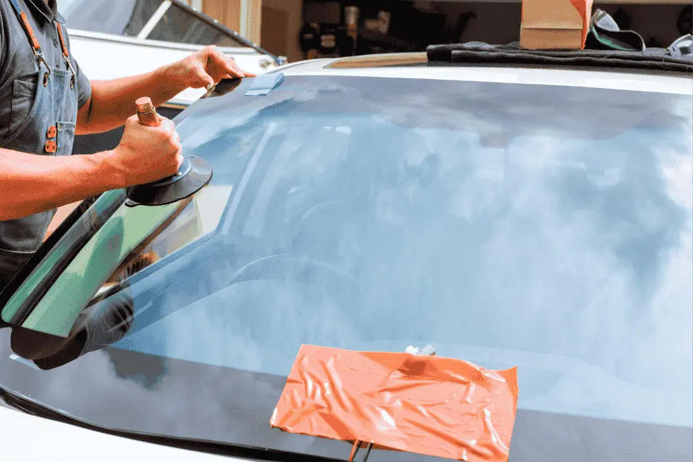 Technician positioning a windshield with a suction-cup handle